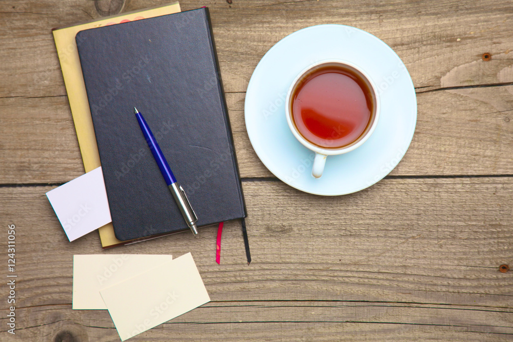 Blank business cards with pen, notebook and tea cup on wooden office table Blank business cards with pen, notebook and tea cup on wooden office table