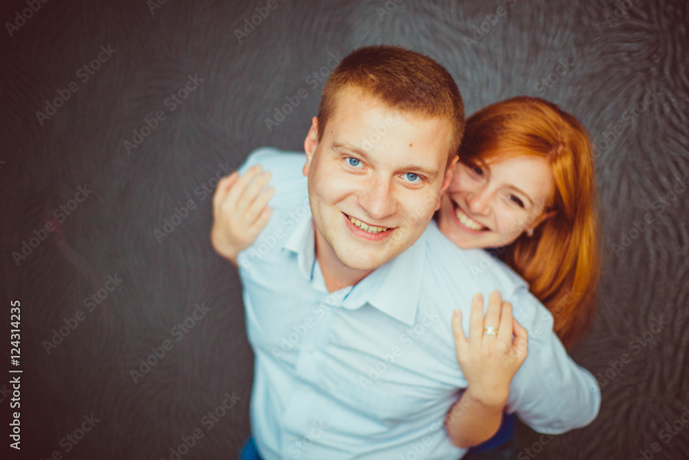 Smiling blond man holds a woman with red hair on his shoulders Smiling blond man holds a woman with red hair on his shoulders