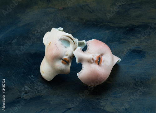 Broken doll face parts isolated on grunge grey and black backgro