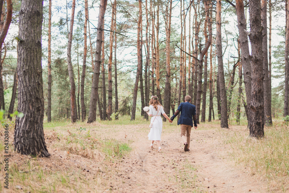 Bride and groom in casual clothes walking in pine forest Bride and groom in casual clothes walking in pine forest