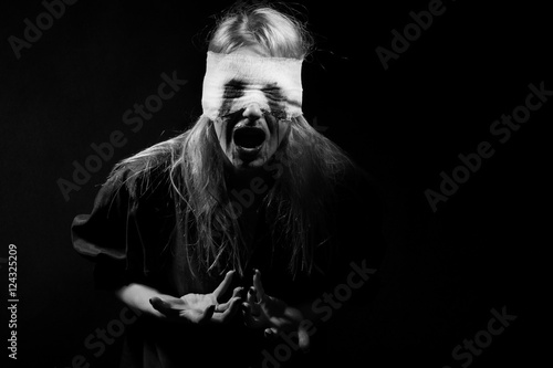 scared bloody girl screaming on black background with copyspace, monochrome
