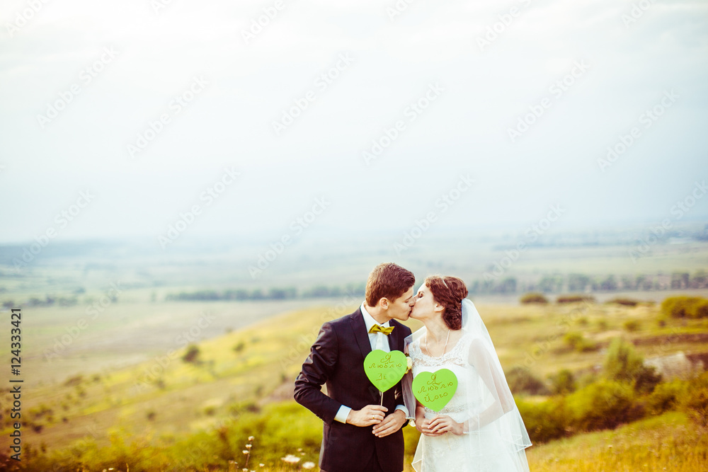 Newlyweds kiss holding in their arms green paper hearts