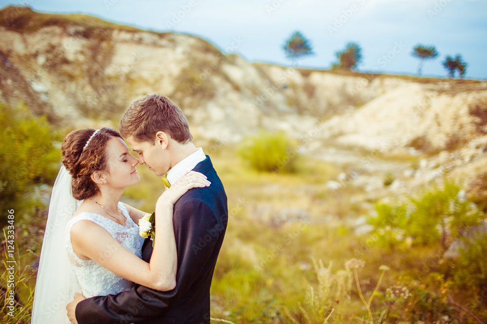 Calm moment between charming newlyweds standing on the field