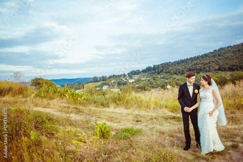 Autumn blue sky hangs over the wedding couple holding each other
