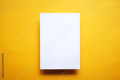 Empty white paper sheet isolated yellow background