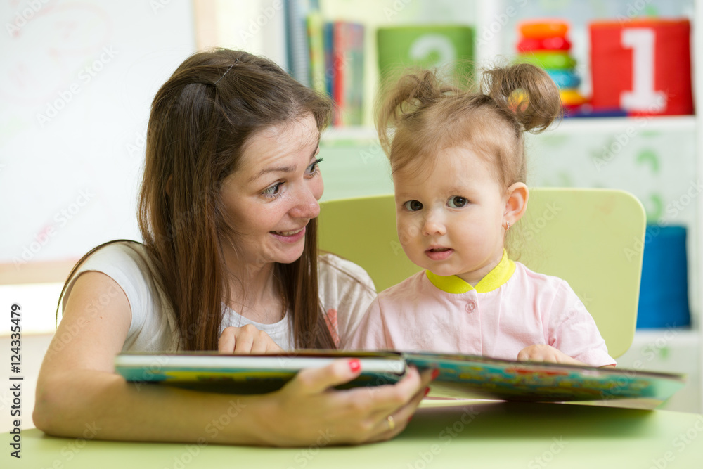Mother reading book her child in nursery Mother reading book her child in nursery
