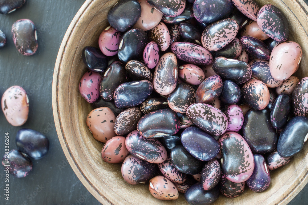 Obraz premium purple bean seeds of different colors on a black background. vegetarian raw food. food color background. bio food