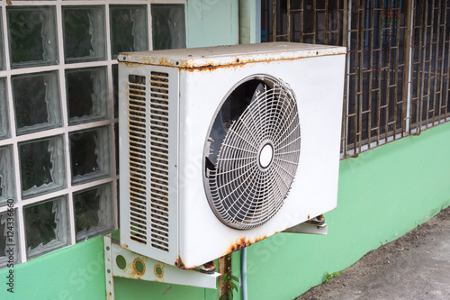 Old air compressor with rust on the wall outdoor