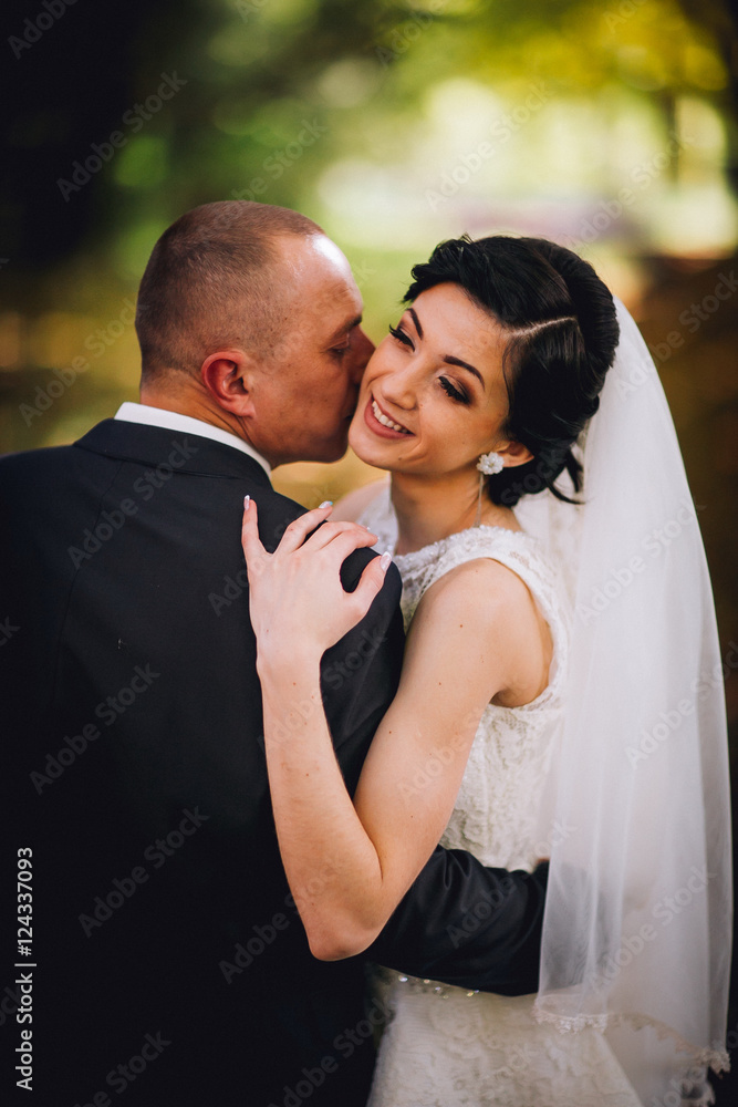 Kissing bride and groom in their wedding day near autumn tree in the forest Kissing bride and groom in their wedding day near autumn tree in the forest