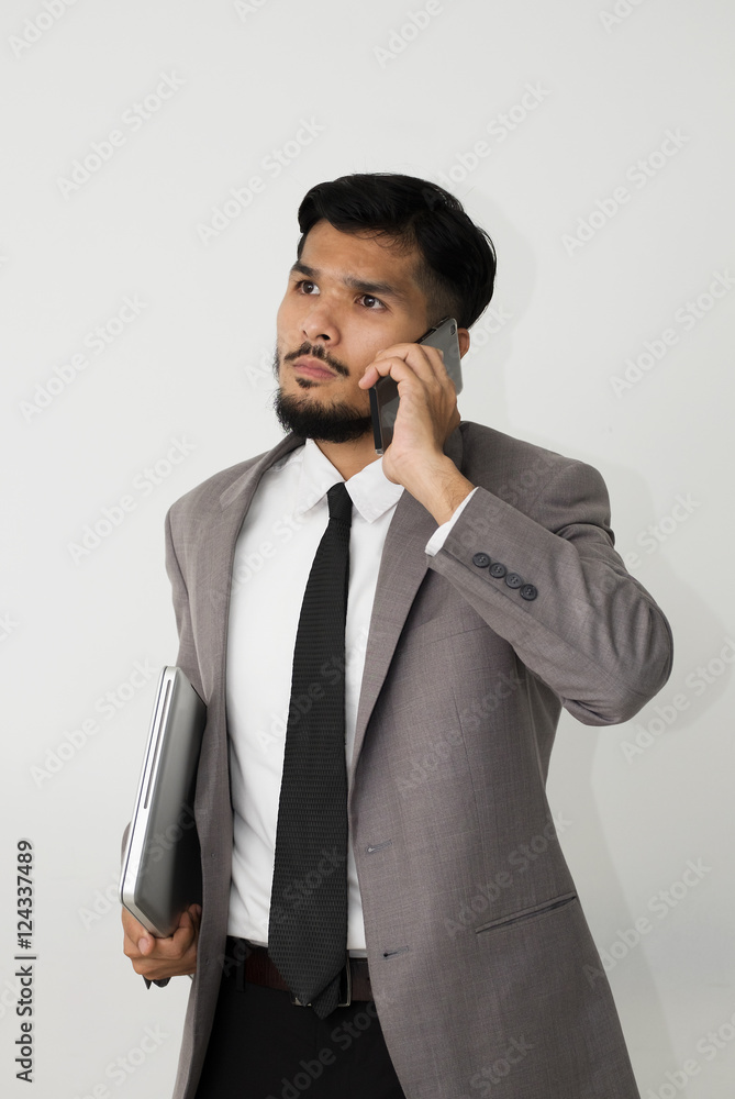 Smart businessman standing  holding a laptop and talk to smartphone