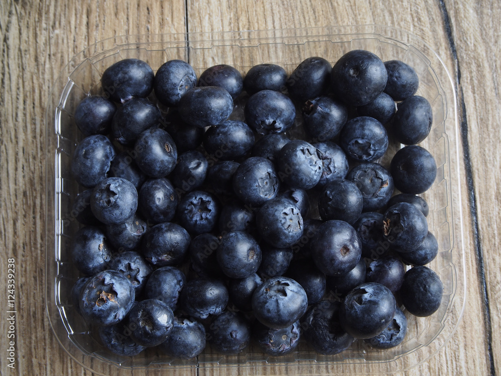 Blueberries in the container on wood backgroung Blueberries in the container on wood backgroung