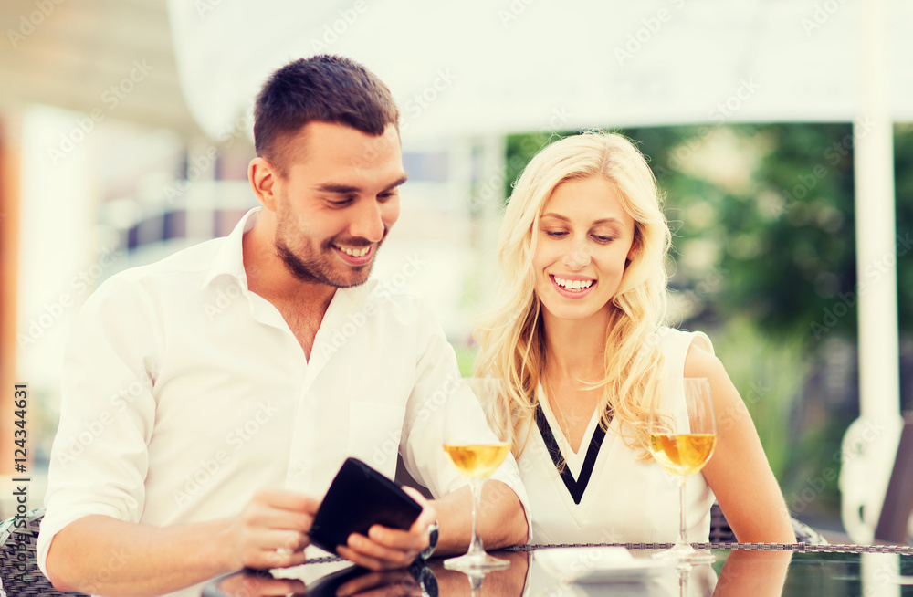happy couple with wallet and bill at restaurant
