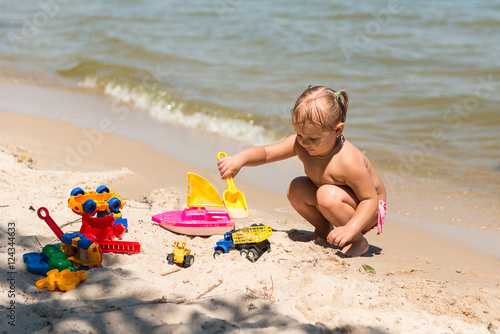 Children playing on the beach, build sand castles, sunbathing. Summer vacation. Parenting and child entertainment.