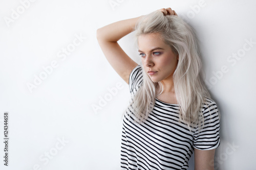 Fotótapéta beautiful young blond woman posing while leaning on white wall