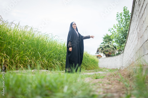 Bild auf Leinwand Beautiful happy Muslim woman in green field