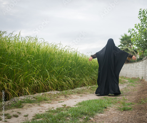 Beautiful happy Muslim woman in green field