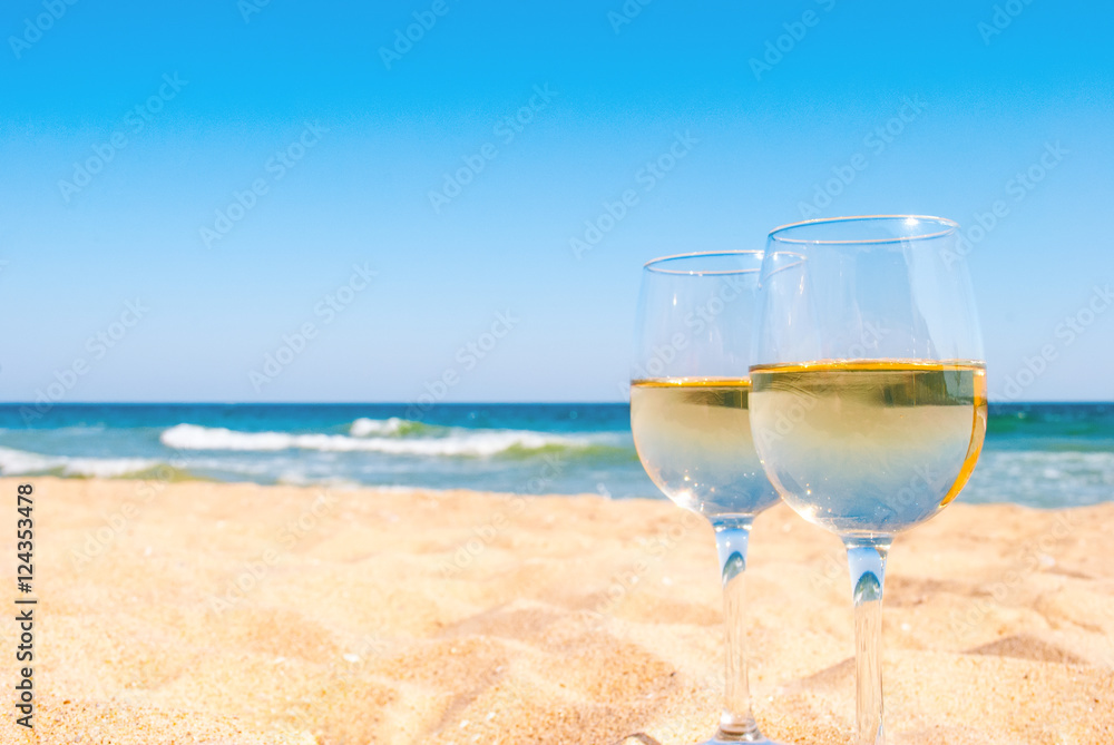 Two glasses of white wine on tropical beach. Romantic idea for couple.
