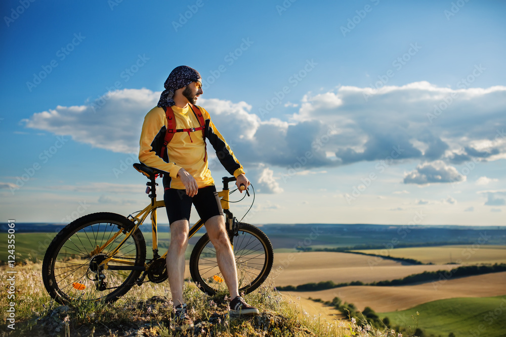 Cyclist riding a bike on off road to the sunset Cyclist riding a bike on off road to the sunset