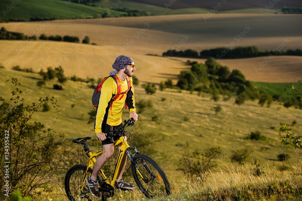 Young cyclist on a rural road through green spring meadow Young cyclist on a rural road through green spring meadow