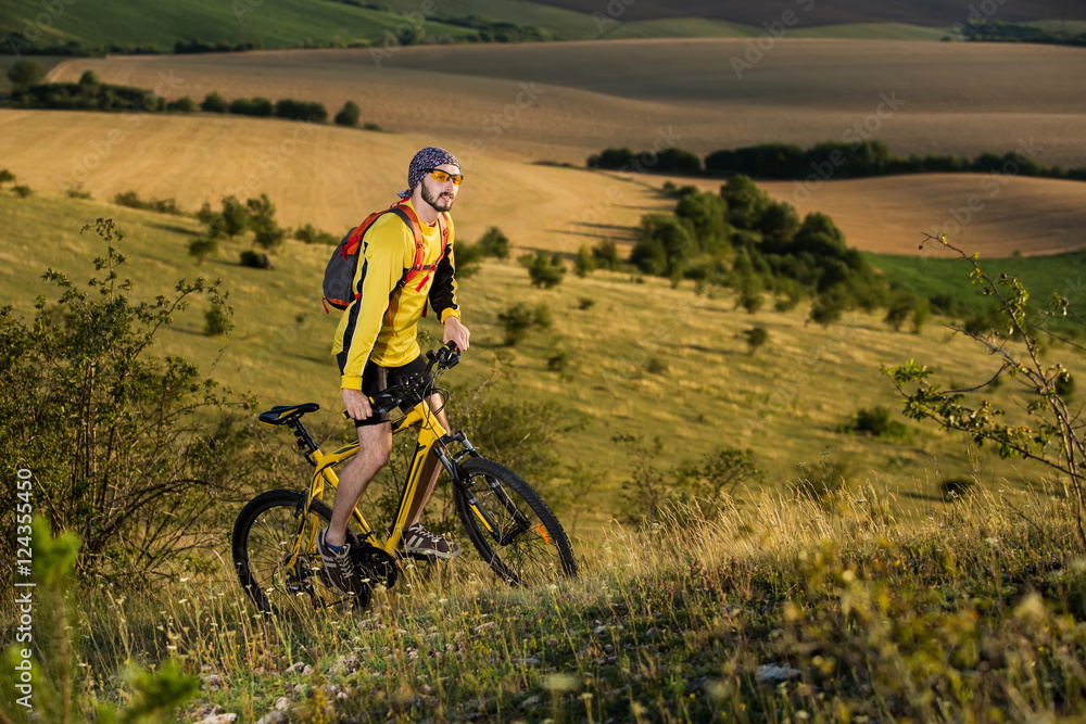 Young cyclist on a rural road through green spring meadow Young cyclist on a rural road through green spring meadow