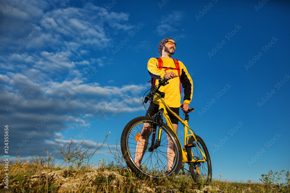 Cyclist man standing on top of a mountain with bicycle