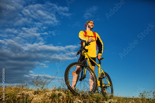 Cyclist man standing on top of a mountain with bicycle