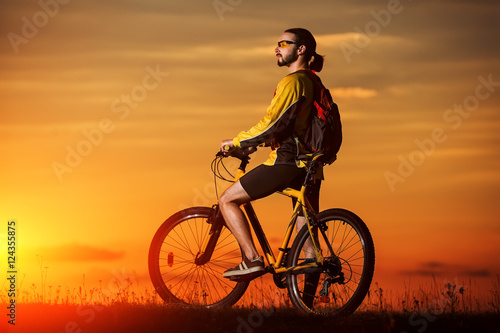 silhouette of the cyclist riding a road bike at sunset