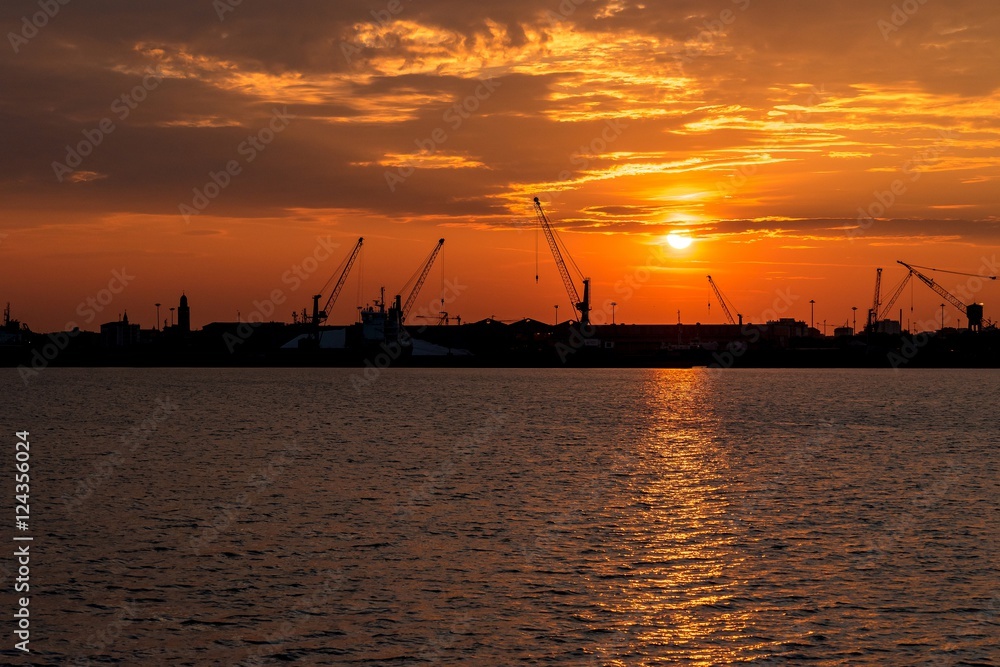 Silhouette of sea port cranes in the morning at sunrise. Chioggia, Italy