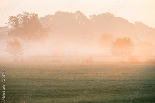 Cyclist on rural road through morning mist. Geesteren. Gelderlan © ysbrandcosijn
