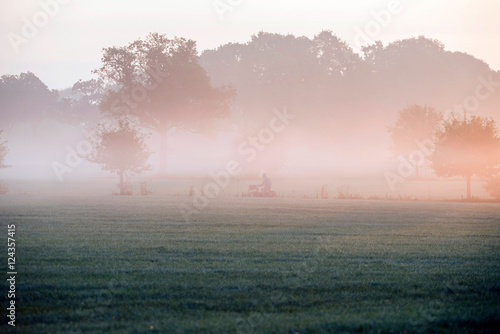Cyclist on rural road through morning mist. Geesteren. Gelderlan