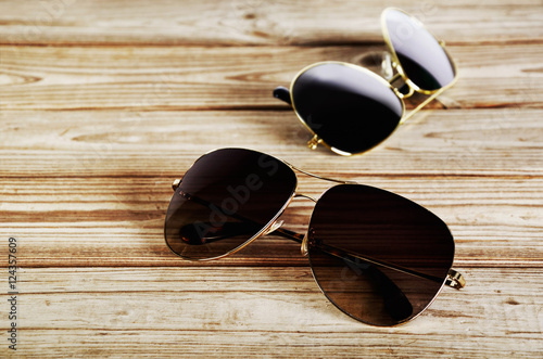 two unisex sunglasses close-up on a wooden background top view