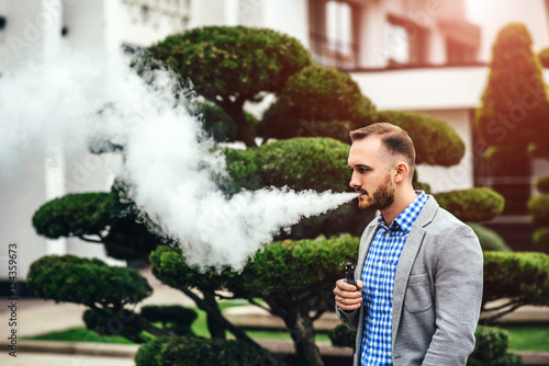 Men with beard smoking electronic cigarette outdoor photo