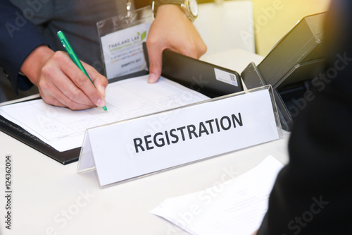 close-up of registration desk in front of conference center with Businessman Writing on the Table photo