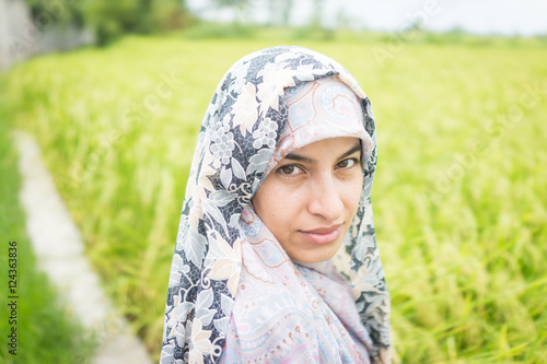 Beautiful happy Muslim woman in green field