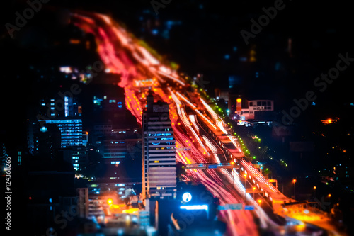 Tilt shift blur effect. Futuristic night cityscape aerial view panorama with illuminated skyscrapers and city traffic across streets. Bangkok, Thailand