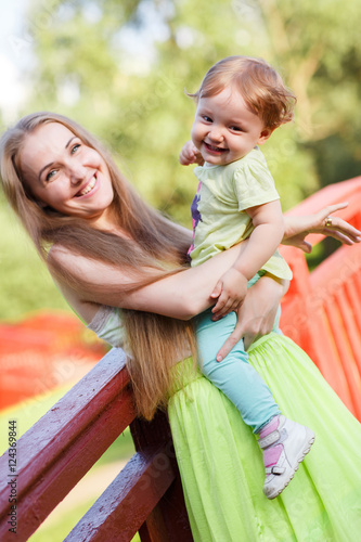 Happy mother and daughter on bridge in park