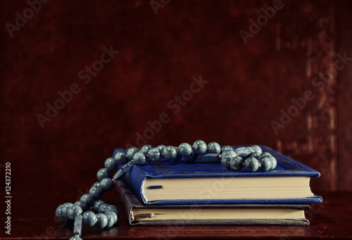 Rosary beads and prayer books on table