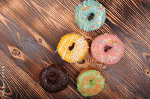Fresh tasty donuts in soft colorful glaze on a grunge dark aged wooden background
