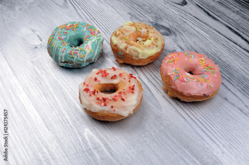 Fresh tasty donuts in soft colorful glaze on a silver wooden background