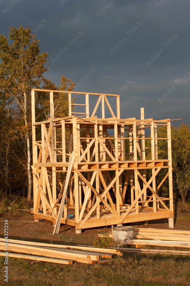 Obraz premium Sunny evening at the construction site of a wooden house. Unfinished house. 