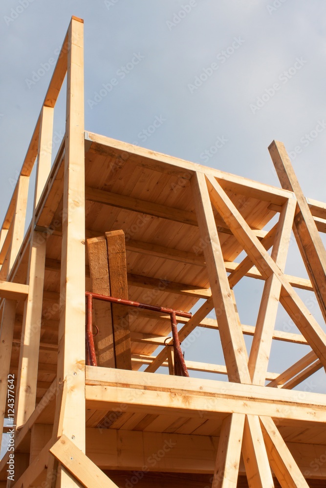 Obraz premium Sunny evening at the construction site of a wooden house. Unfinished house. 