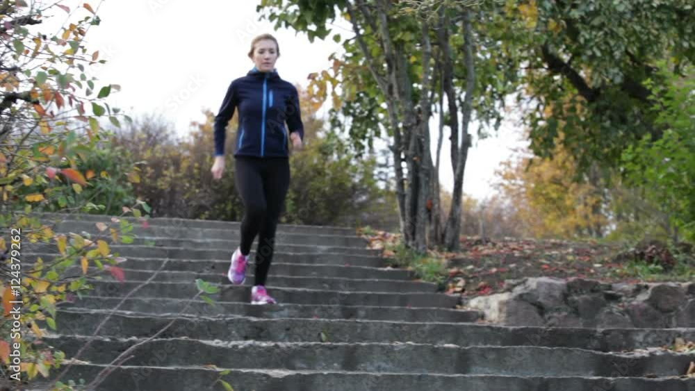 Young woman running down the stairs and going on the scamper in the autumn park Young woman running down the stairs and going on the scamper in the autumn park