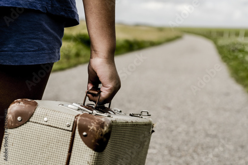 Fotografía Refugee child goes on the road with her  suitcase