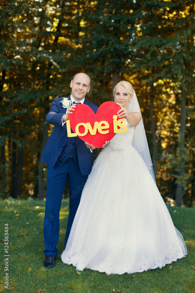 Newlyweds are holding a red heart Newlyweds are holding a red heart