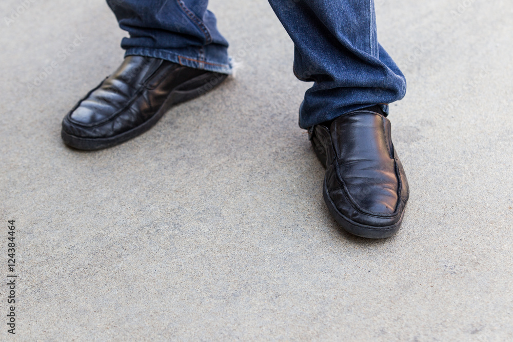 Black leather shoes on concrete floor.