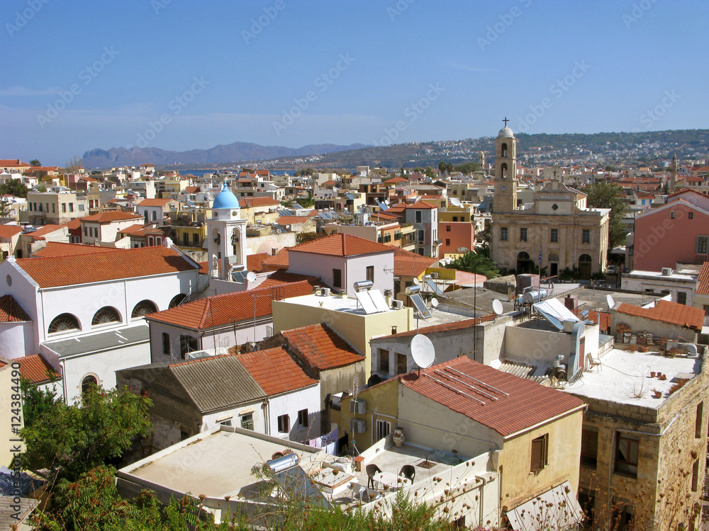 Greece, Crete. Panorama of Chania old town aerial view. Old houses with red roofs, Cathedral and Catholic church. On rear background are mountains and sea.