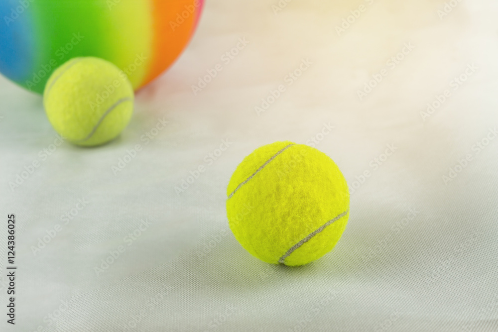 tennis balls and rainbow colored plastic ball on white ground