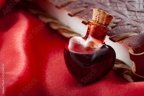 Fototapeta Love potion leaning on a book of magic spells for Valentine's day