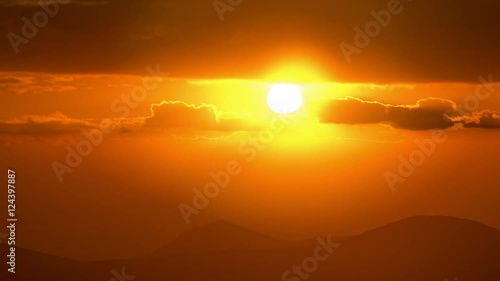 Vivid sunrise over silhouetted hills,bright red sun, timelapse.