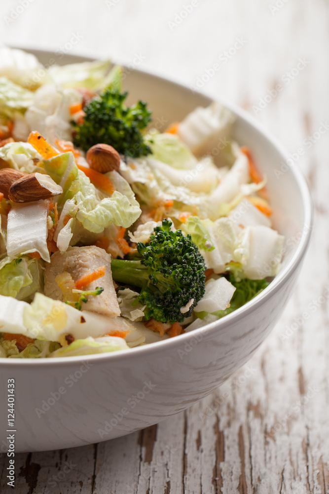 Asian Napa cabbage salad with organic broccoli, almonds, chicken, and a rice vinaigrette in a white bowl - macro shot Asian Napa cabbage salad with organic broccoli, almonds, chicken, and a rice vinaigrette in a white bowl - macro shot